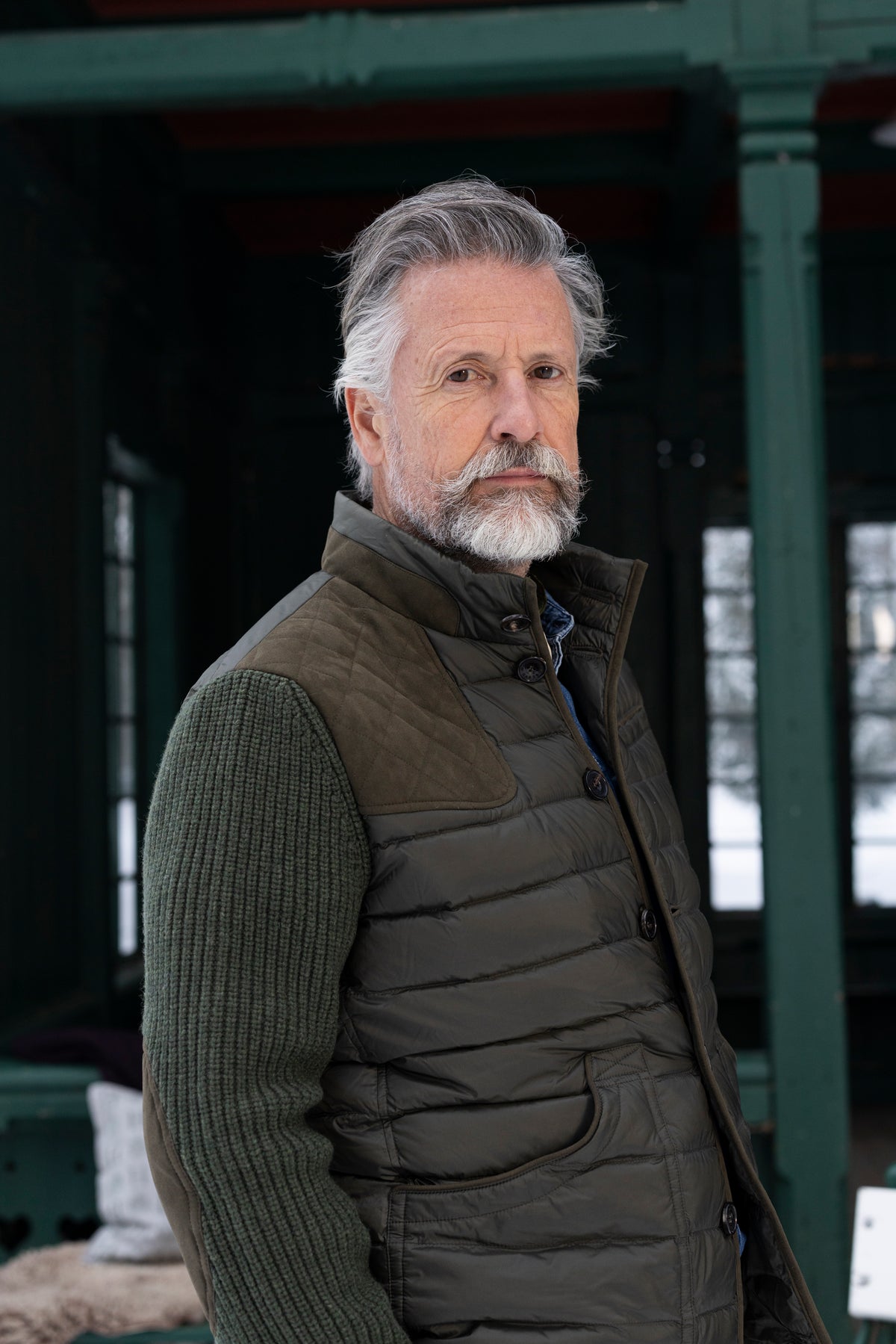 Model in Herren-Daunenjacke Saxenegg mit Strickärmeln in dunklem Grün.